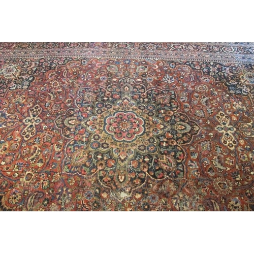 924 - A large Persian carpet c 1920's, central motif on pale red ground, with very wide blue/red/cream bor... 