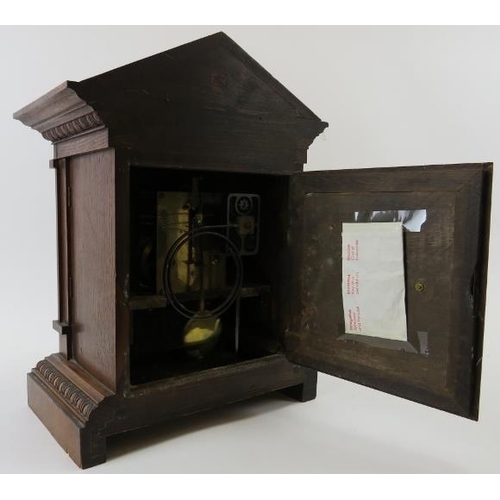 265 - Junghans mantle clock. Architectural oak case, coil strike, with key included. Bevelled glazed doors... 