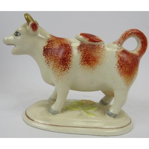 36 - A late Victorian ceramic Ayrshire cow creamer. Hand painted with gilt highlights and supported on an... 