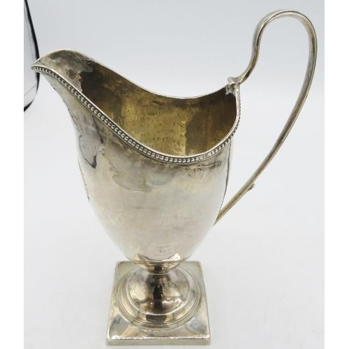 433 - A Georgian silver helmet shaped cream jug on square base and bead edge decoration. Engraved motto 'U... 