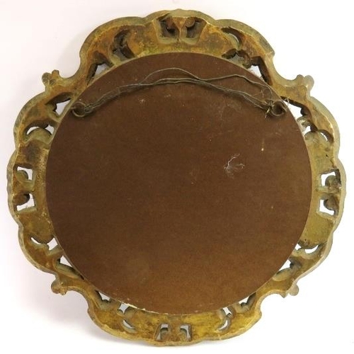 69 - A gilt carved wood Florentine style convex mirror. The circular mirror carved in openwork with scrol... 