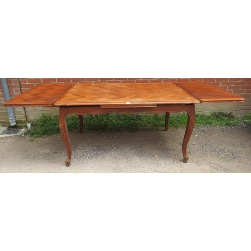 741 - A vintage French walnut draw-leaf extending dining table, the shaped top with parquetry inlay, on ac... 