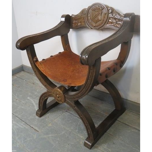 749 - A vintage mahogany X-frame ‘Savanorola’ chair, the back carved with a heraldic crest, the heavy gaug... 