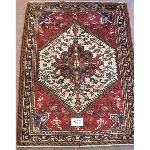 927 - A Persian Heriz rug, with a cream hexagonal central panel on a red ground. 168cm x 110cm (approx).