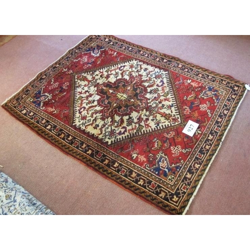 927 - A Persian Heriz rug, with a cream hexagonal central panel on a red ground. 168cm x 110cm (approx).