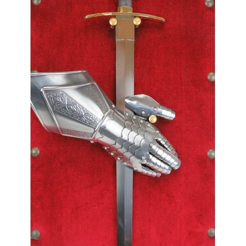 116 - A sword and gauntlet mounted on a studded red velvet shield, 20th century. 40.1 in (103 cm) height. ... 