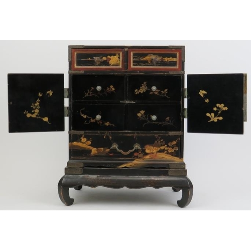 120 - A Japanese lacquered miniature cabinet on stand, Meiji/Taisho period. The hinged doors opening to re... 