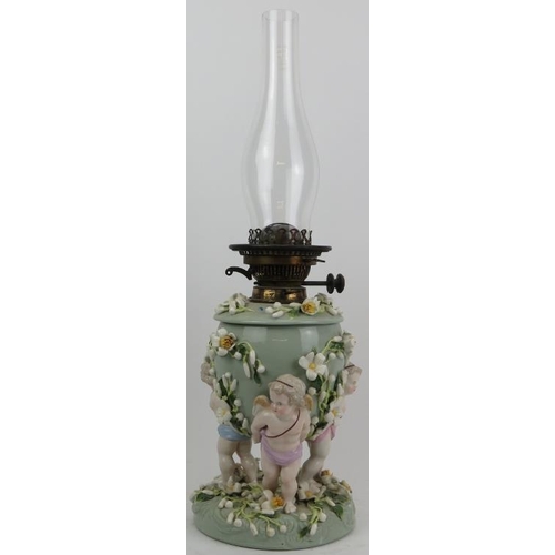 126 - A large European porcelain oil lamp, 19th century. Modelled with three cherubs carrying an urn with ... 