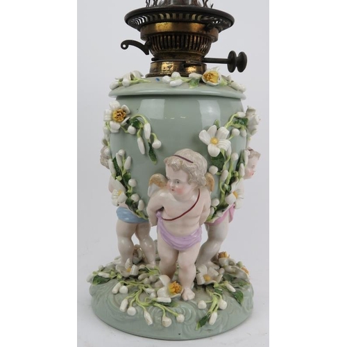 126 - A large European porcelain oil lamp, 19th century. Modelled with three cherubs carrying an urn with ... 