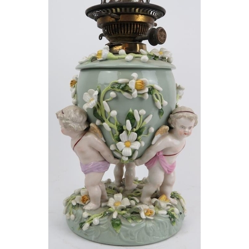 126 - A large European porcelain oil lamp, 19th century. Modelled with three cherubs carrying an urn with ... 