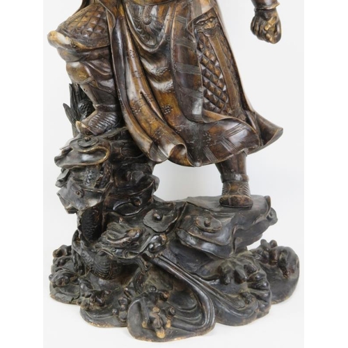 19 - A large Chinese carved wood figure of a warrior. Depicted standing above a dragon amongst clouds. 44... 