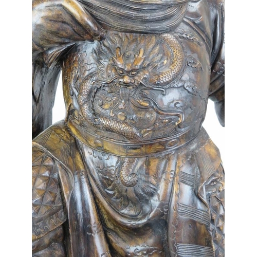 19 - A large Chinese carved wood figure of a warrior. Depicted standing above a dragon amongst clouds. 44... 