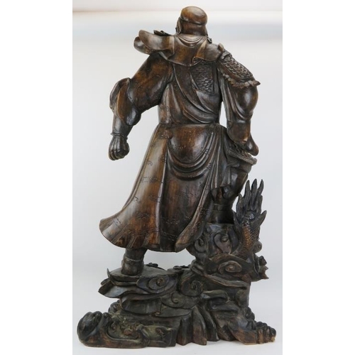 19 - A large Chinese carved wood figure of a warrior. Depicted standing above a dragon amongst clouds. 44... 