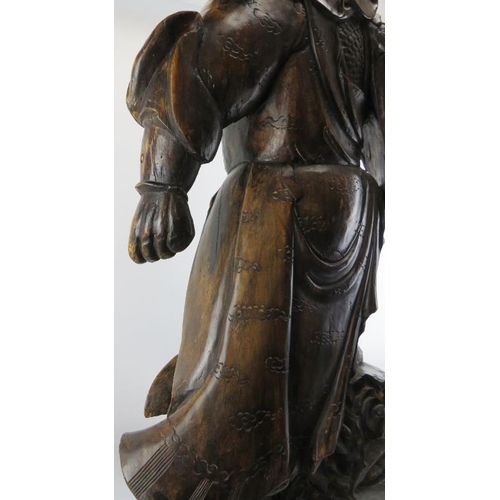 19 - A large Chinese carved wood figure of a warrior. Depicted standing above a dragon amongst clouds. 44... 