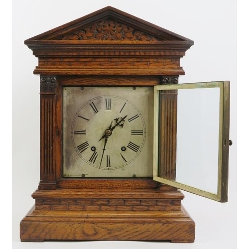 202 - An oak cased Palladian style mantel clock, late 19th/early 20th century. With a bevelled glass front... 