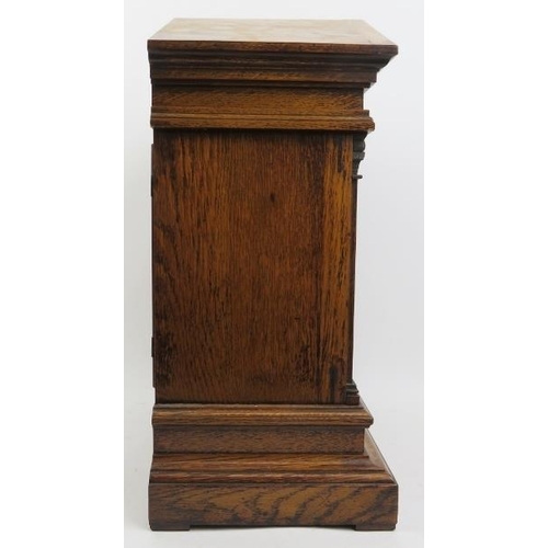 202 - An oak cased Palladian style mantel clock, late 19th/early 20th century. With a bevelled glass front... 