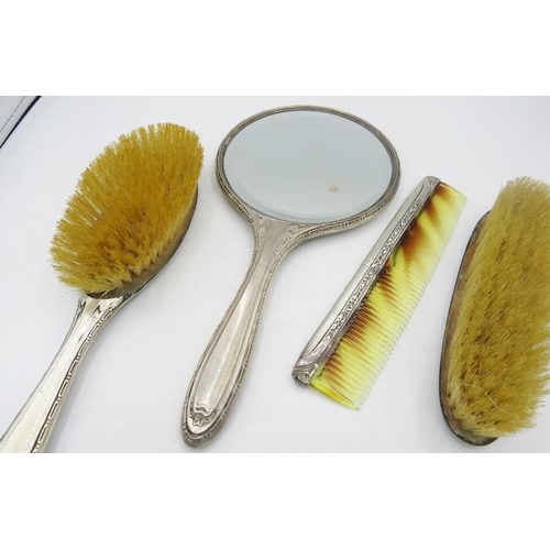 335 - A silver four piece dressing table set comprising of hand mirror, hair brush, comb and clothes brush... 