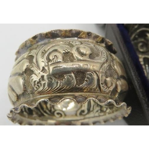 418 - A pair of silver napkin rings heavily embossed with scrolls and foliate design, monogrammed, silver ... 