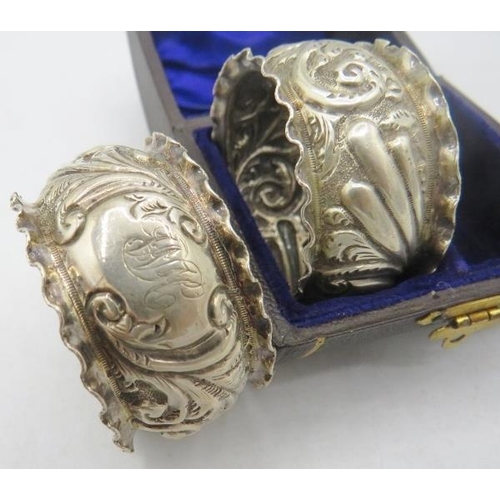 418 - A pair of silver napkin rings heavily embossed with scrolls and foliate design, monogrammed, silver ... 