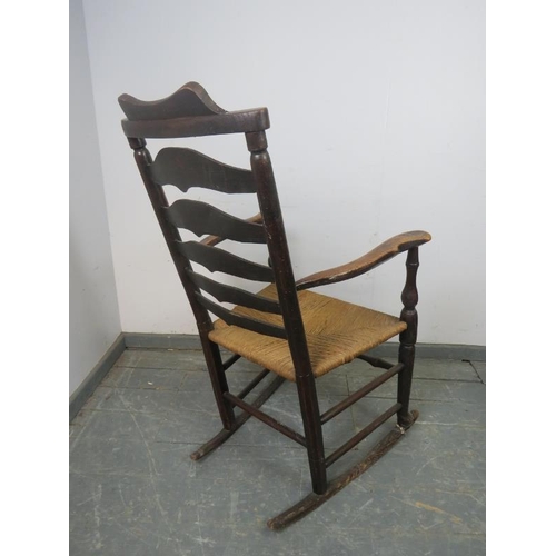 874 - A 19th century elm Lancashire ladderback rocking chair, with rush seat, on turned supports with stre... 