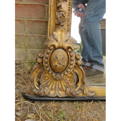 705 - A large Victorian arched over-mantle mirror, the gilt gesso frame with shell cornice amidst scrollin... 