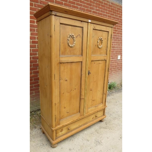 723 - An antique Continental pine double wardrobe, the panelled doors opening onto a loose shelf above a h... 