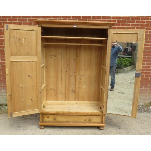 723 - An antique Continental pine double wardrobe, the panelled doors opening onto a loose shelf above a h... 