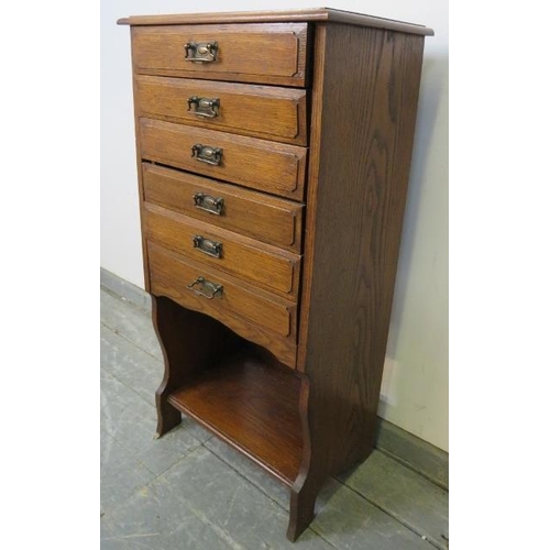 744 - An Edwardian oak music cabinet, housing six long drawers with hinged fronts, above an open shelf, on... 