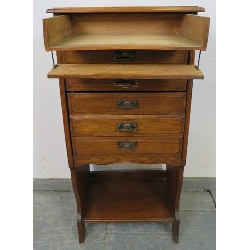 744 - An Edwardian oak music cabinet, housing six long drawers with hinged fronts, above an open shelf, on... 