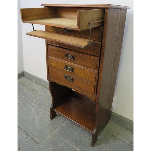 744 - An Edwardian oak music cabinet, housing six long drawers with hinged fronts, above an open shelf, on... 