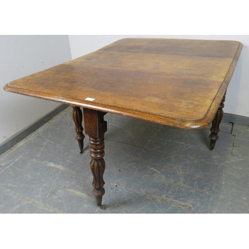 757 - A Victorian walnut drop-leaf table, on tapering turned and fluted supports with brass caps and casto... 