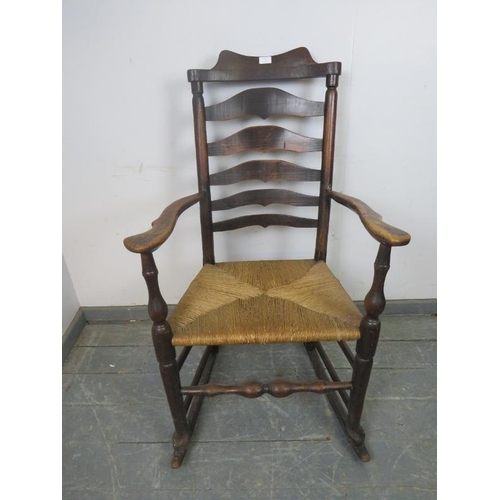 874 - A 19th century elm Lancashire ladderback rocking chair, with rush seat, on turned supports with stre... 