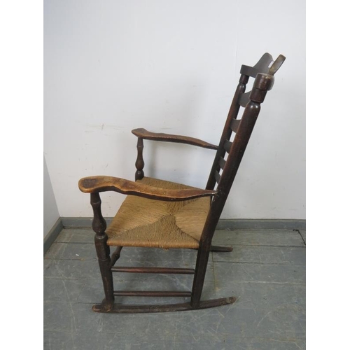 874 - A 19th century elm Lancashire ladderback rocking chair, with rush seat, on turned supports with stre... 