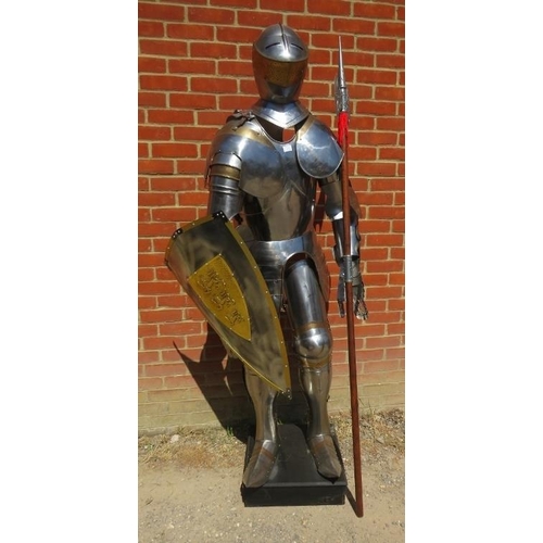 878 - A life-size replica 16th century knight’s suit of armour in steel plate and brass, on a plinth base.... 