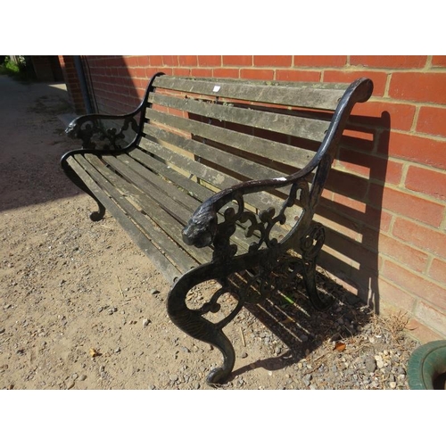 885 - A weathered cast iron scroll back garden bench with teak slatted seat, on pierced end supports with ... 