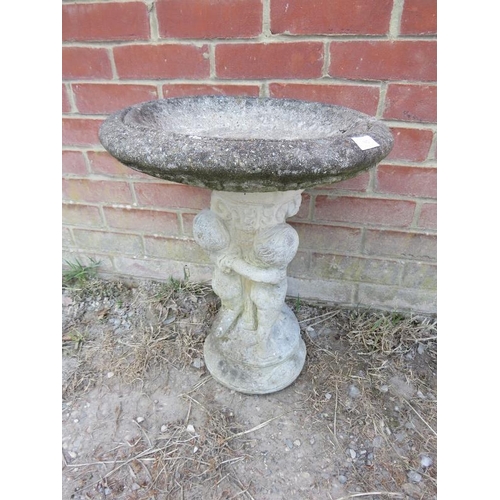 892 - A weathered reconstituted stone birdbath, the base in the form of cherubs frolicking in the Classica... 