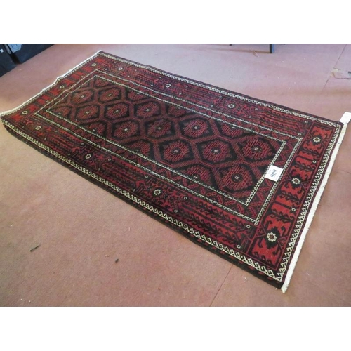 909 - A North East Persian meshed Belouch rug deep burgundy high lighted with black and white. In good con... 