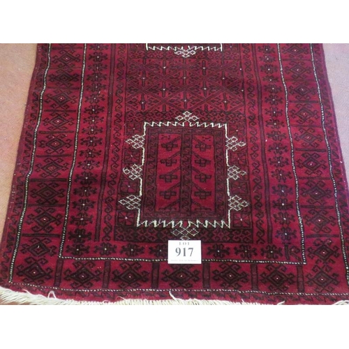 917 - A Persian meshed rug, 3 central motifs on a burgundy ground. 216 x 120.