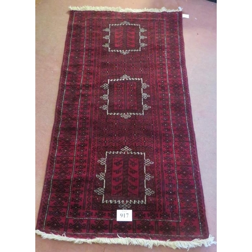 917 - A Persian meshed rug, 3 central motifs on a burgundy ground. 216 x 120.