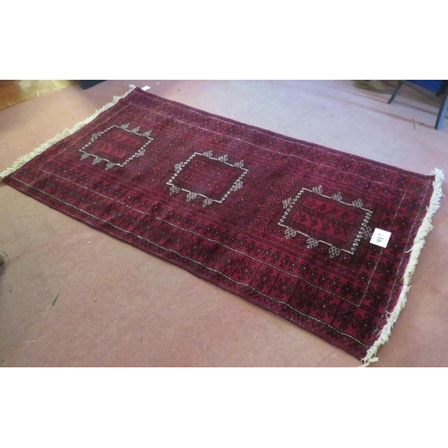 917 - A Persian meshed rug, 3 central motifs on a burgundy ground. 216 x 120.