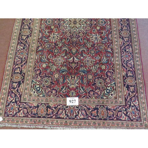 927 - A Persian Ardkan carpet central heavy floral patterns on red ground with wide blue borders. In good ... 