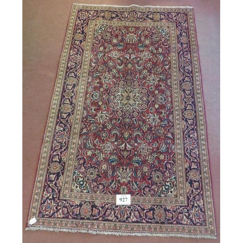 927 - A Persian Ardkan carpet central heavy floral patterns on red ground with wide blue borders. In good ... 