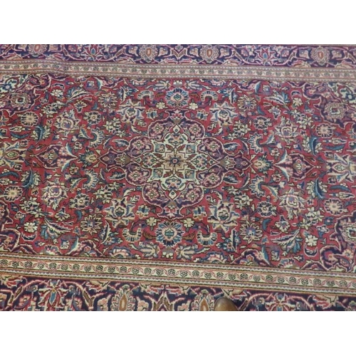 927 - A Persian Ardkan carpet central heavy floral patterns on red ground with wide blue borders. In good ... 