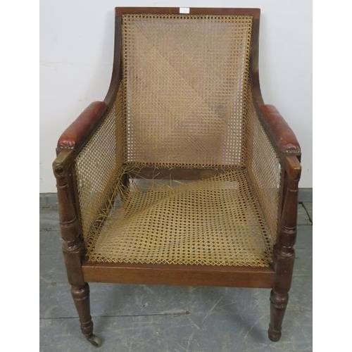 842 - An Regency Period bergère library chair, with loose cushions upholstered in oxblood buttoned leather... 