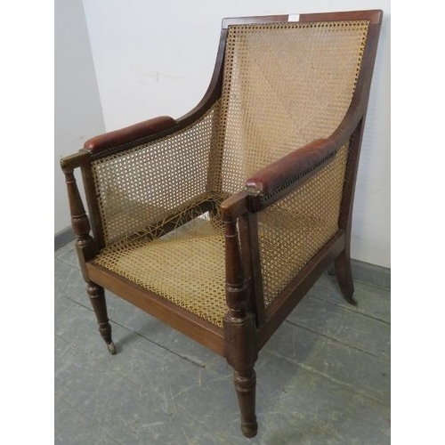 842 - An Regency Period bergère library chair, with loose cushions upholstered in oxblood buttoned leather... 