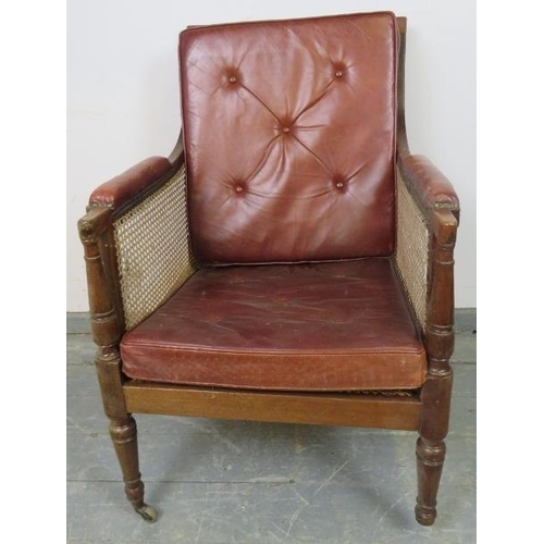 842 - An Regency Period bergère library chair, with loose cushions upholstered in oxblood buttoned leather... 