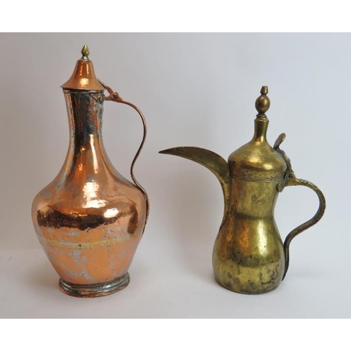 221 - Two Middle Eastern metalwork decanters. Comprising a copper jug with hinged cover together with a br... 