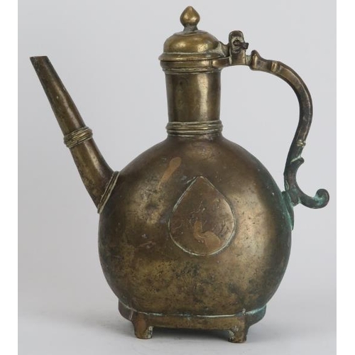 30 - A Mughal Indian engraved brass ewer, 18th century. Of bulbous form with a hinged cover and supported... 