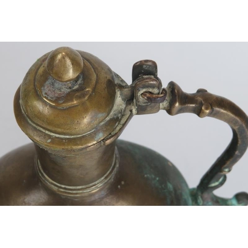 30 - A Mughal Indian engraved brass ewer, 18th century. Of bulbous form with a hinged cover and supported... 