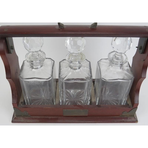 35 - A three glass decanter tantalus set, 20th century. With brass mounts. 16 in (40.7 cm) length. 
Condi... 